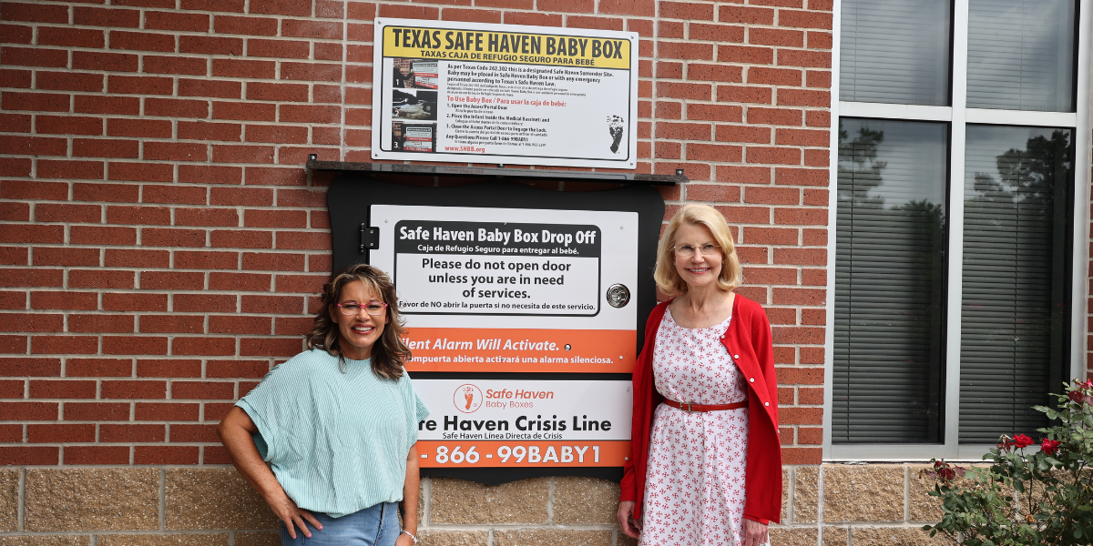 Photo of two smiling people standing in front of a Safe Haven Baby Box