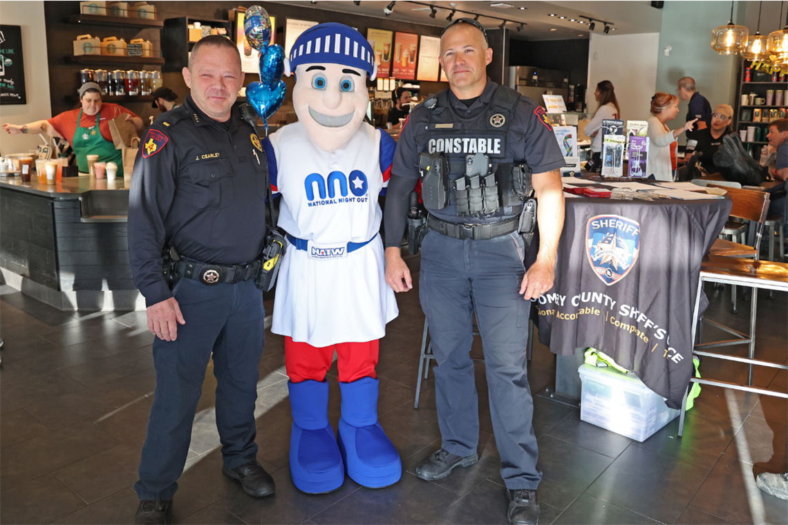 Photo of two police officers dressed in blue with a mascot dressed in red, white and blue.