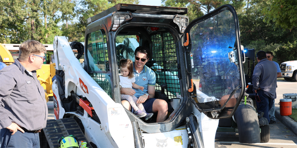 Photo of a child sitting in a large front loader looking at the controls