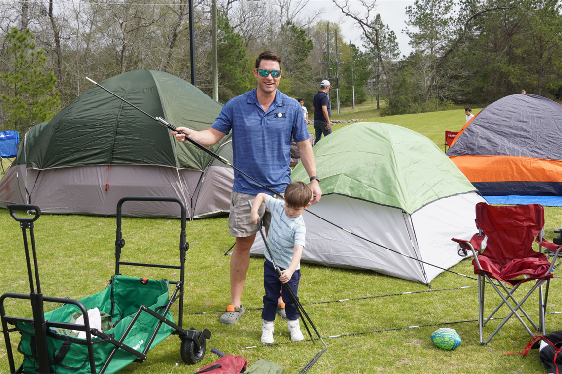 Photo of a father and son standing next to outdoor tents