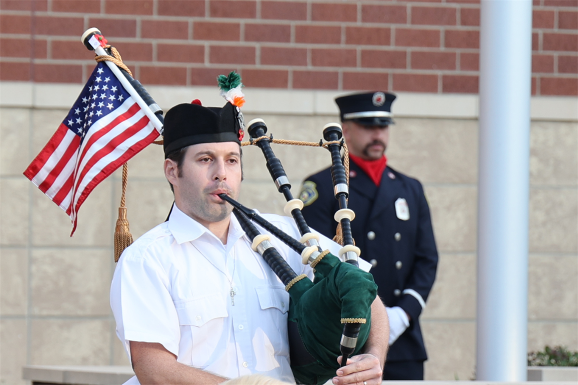 Photo of person playing the bagpipes and an American flag