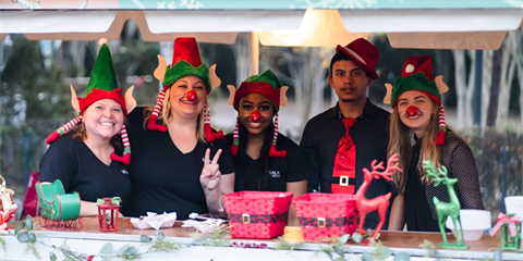 Photo of a group of smiling people wearing elf hats