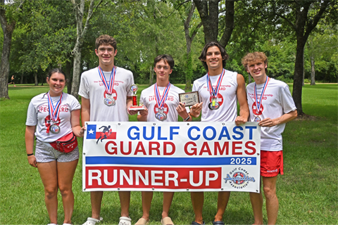 Lifeguards standing on grass holding a competition runner up banner