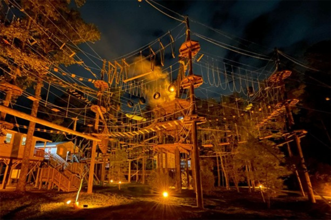 Nighttime photo of aerial obstacle course with ropes and planks