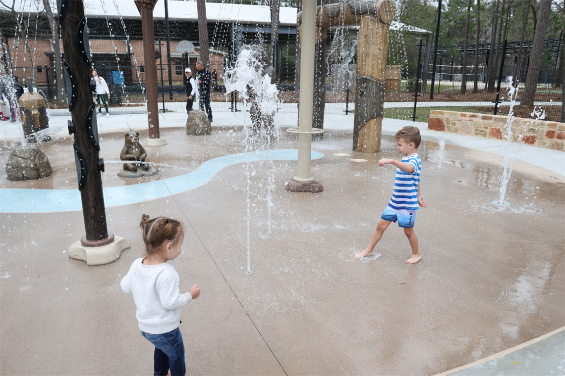 Photo of 2 children playing under water fountains