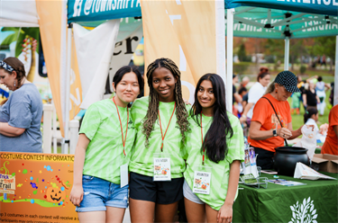 Photo of three smiling teenagers wearing green tshirts