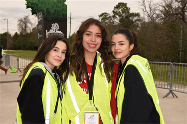 Photo of three smiling teenagers wearing green safety vests