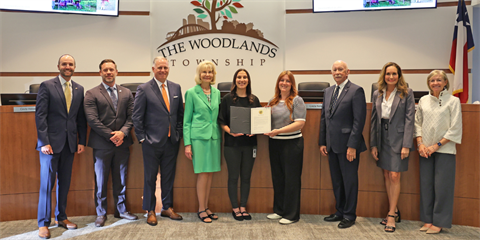 Group of smiling people standing in a Boardroom holding an award