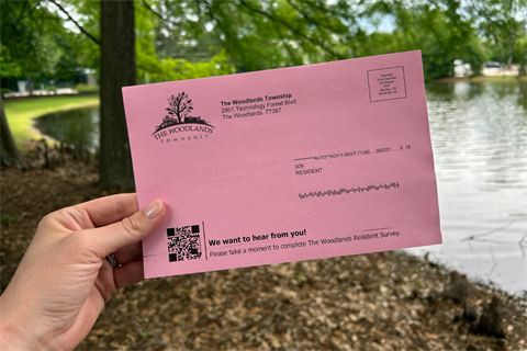 A hand holding a pink postcard