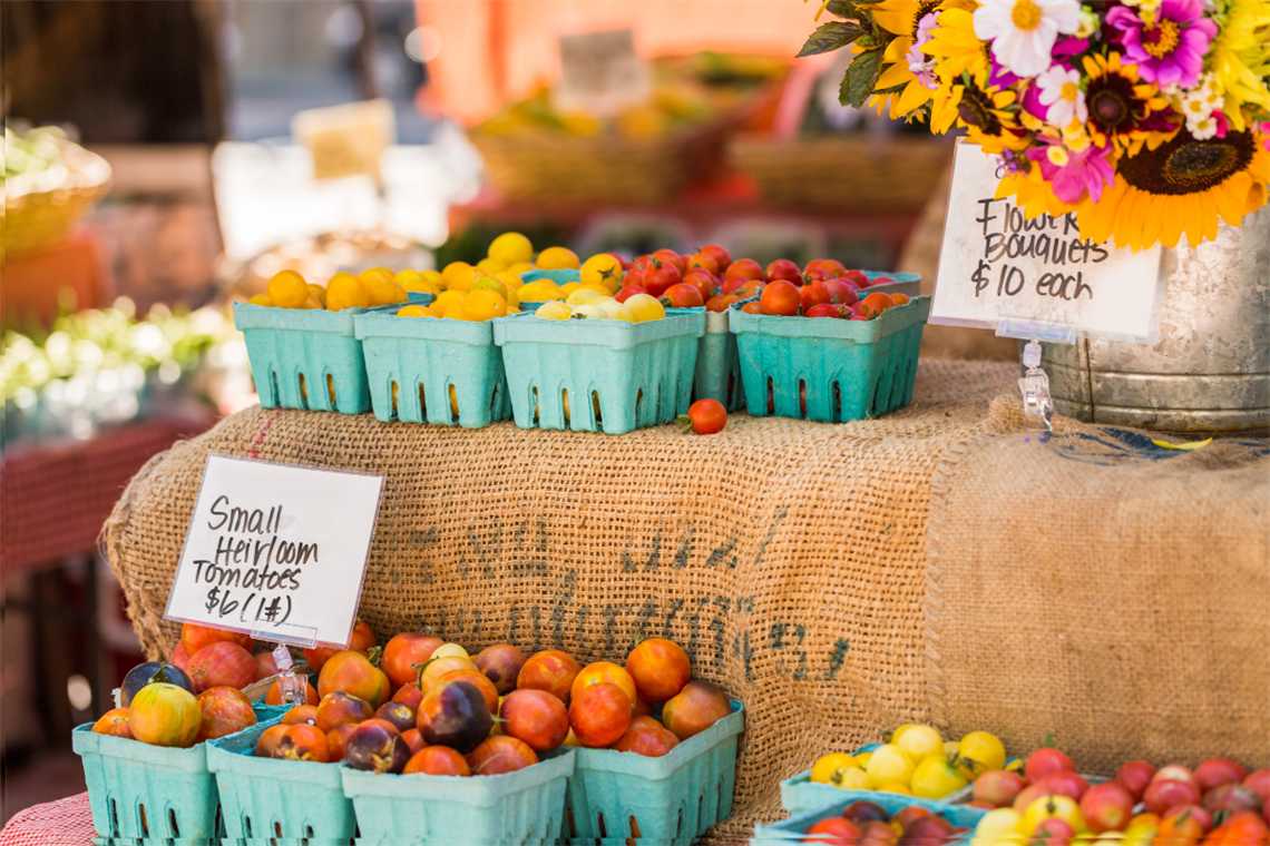 Photo of fresh tomatoes and other vegetables on a burlap covered table