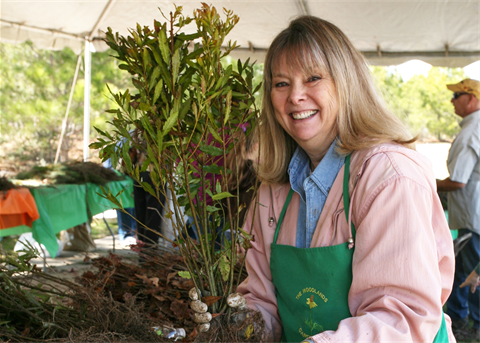 Photo of a smiling woman holding a small tree