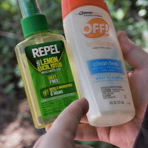 Hands holding two different bottles of insect repellent