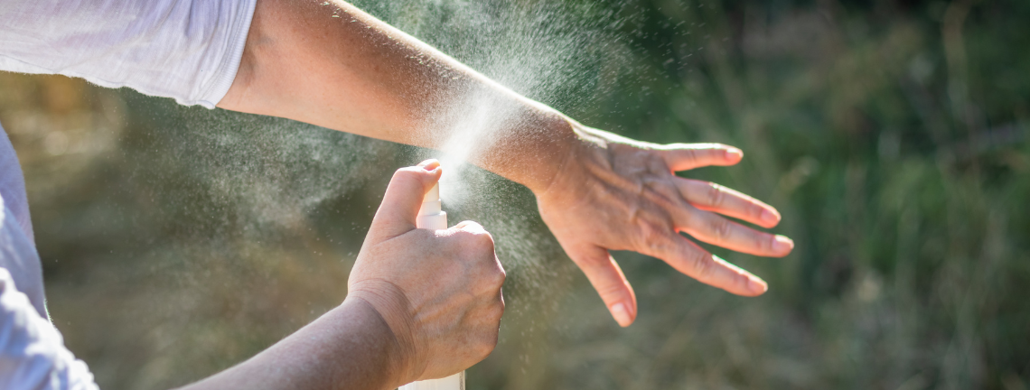 Person using mosquito spray on arm