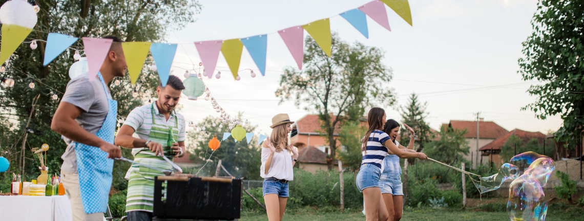People grilling outdoors with visible banners while others are smiling playing with bubbles