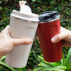 Two people holding reusable travel mugs outside