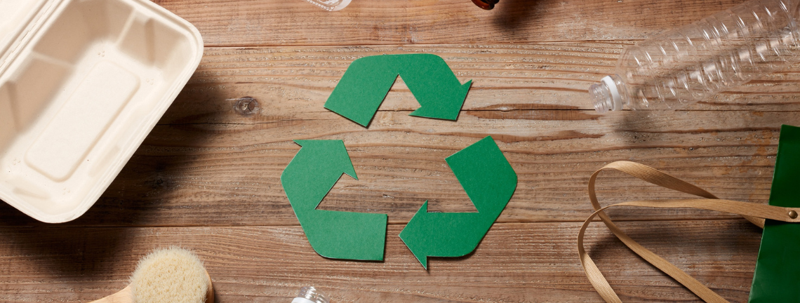 The recycle symbol surrounded by recyclable materials such as a plastic water bottle and a to-go box