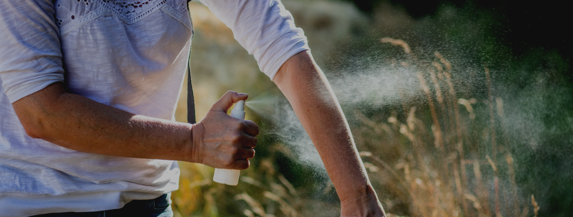 Person spraying their arms with mosquito repellant