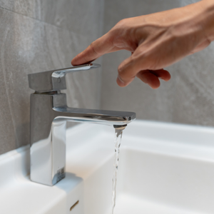 Person turning off a sink faucet