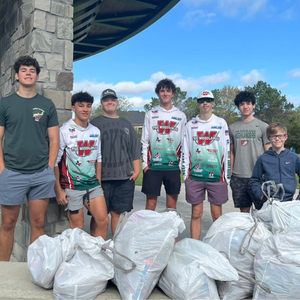 Group of boys outside with full bags of trash in front of them