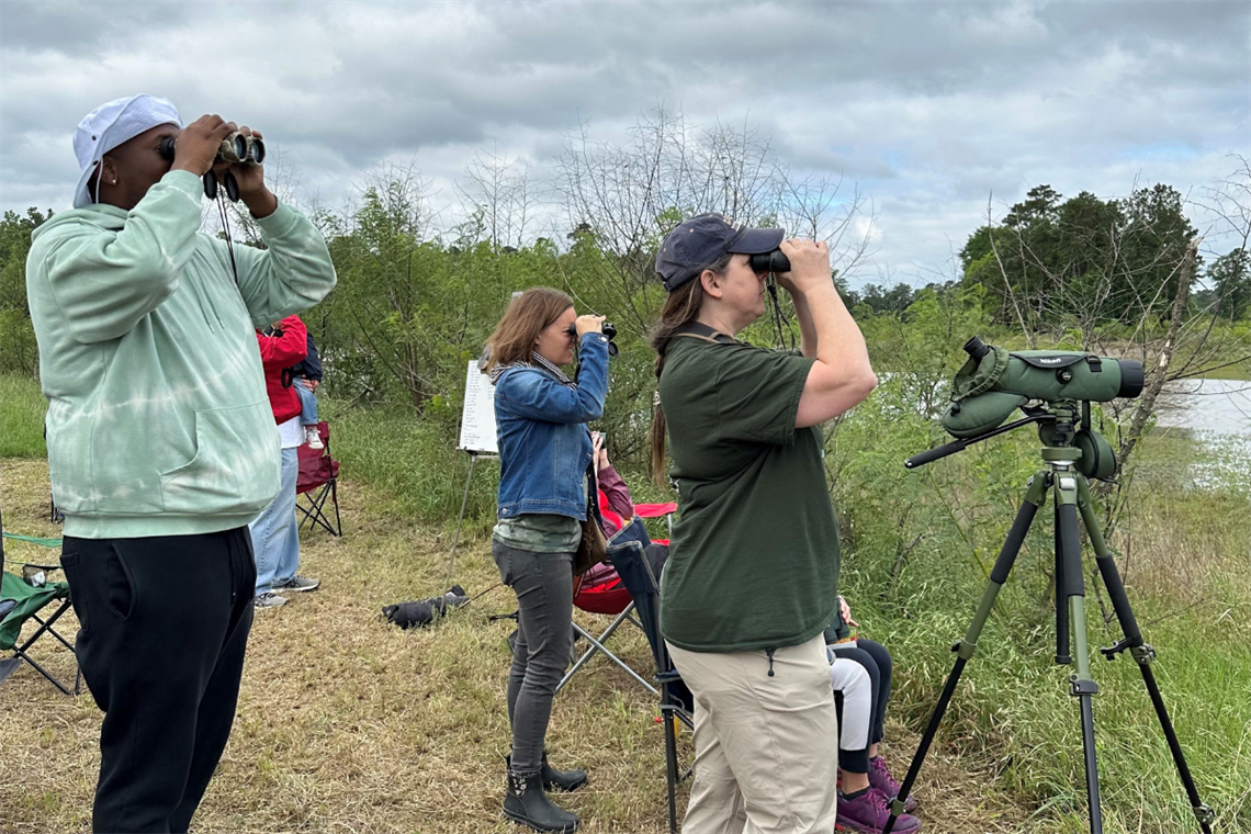 Photo of people with binoculars looking into the sky