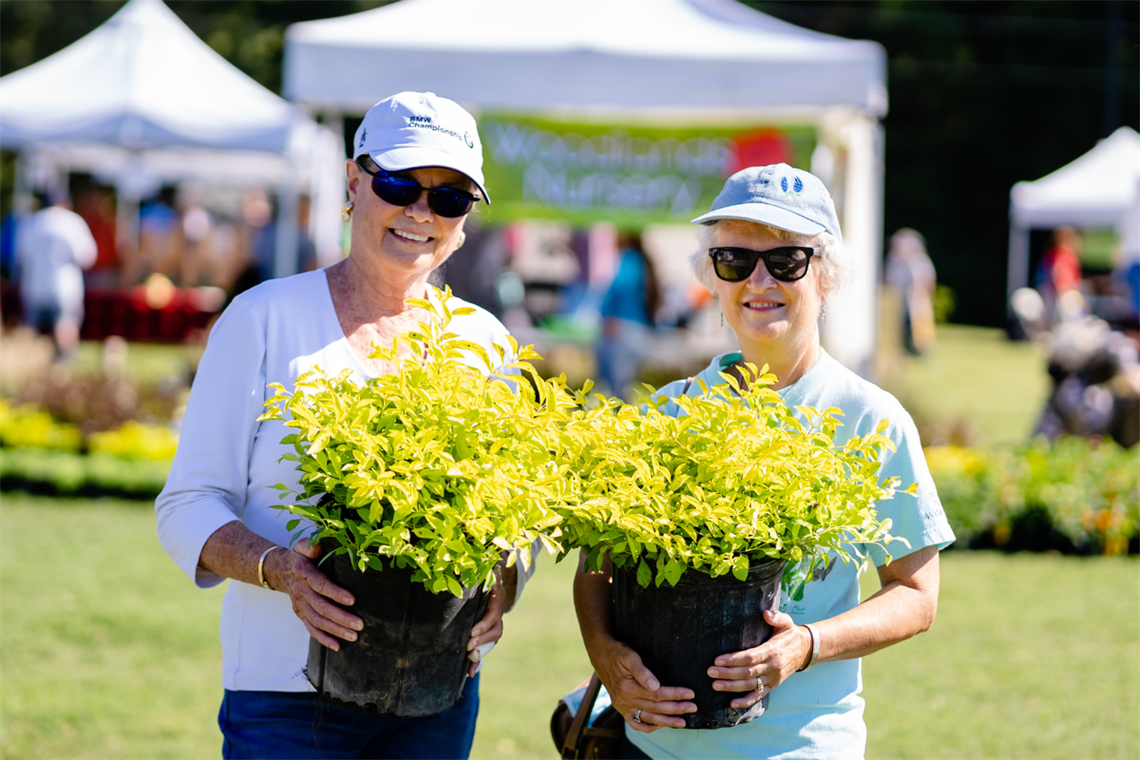 Photo of two smiling people holding yellow-green plants