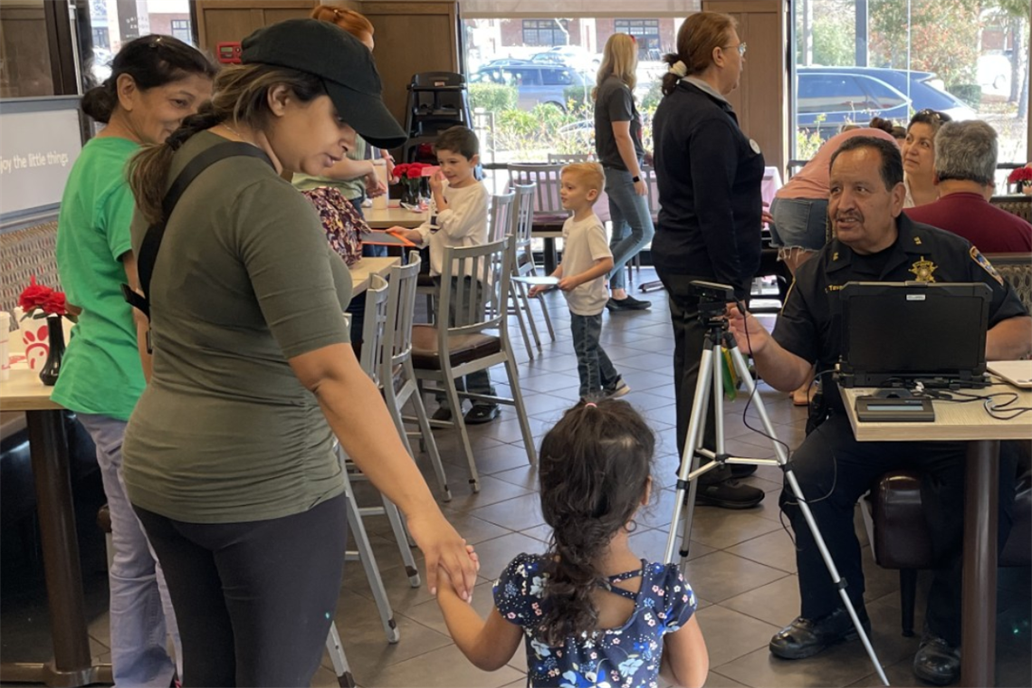 Photo of a police man talking with adults and children.