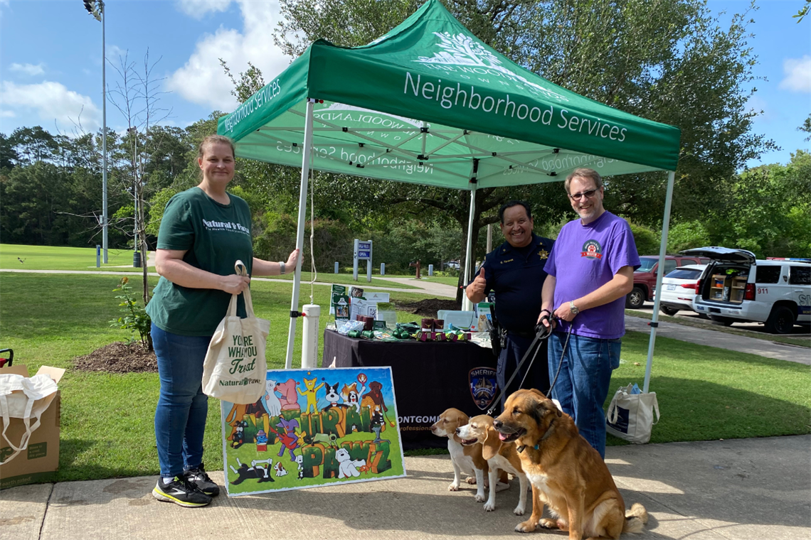 Photo of three smiling people in a park with thier dogs