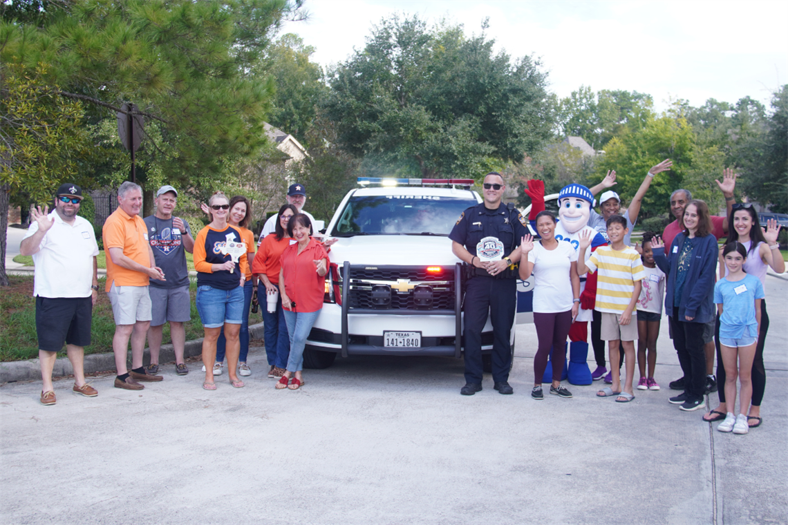 Photo of families and children standing next to a police vehicle with a policeman
