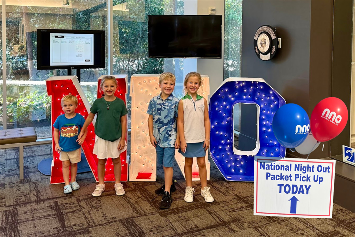 Photo of smiling children standing in front of large NNO letters