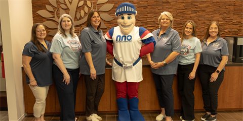 Image of smiling people standing with the Nat the Knight mascot dressed in red, white and blue