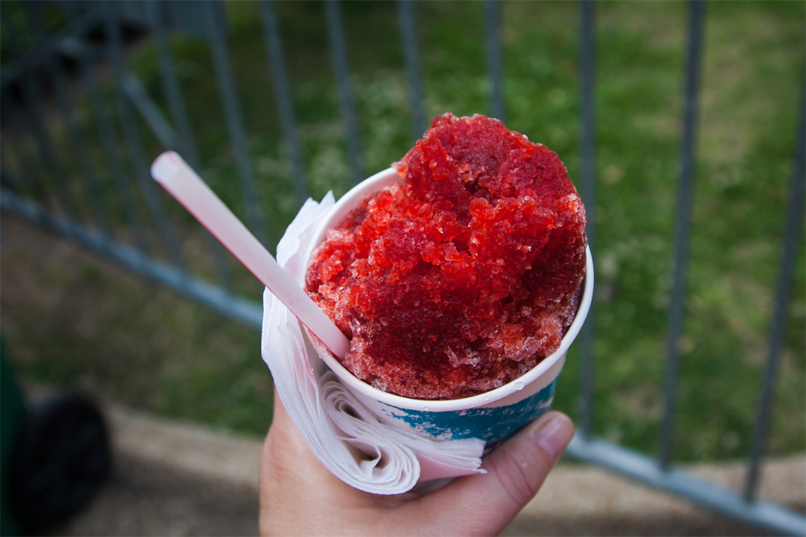 A red snow cone in a paper cup