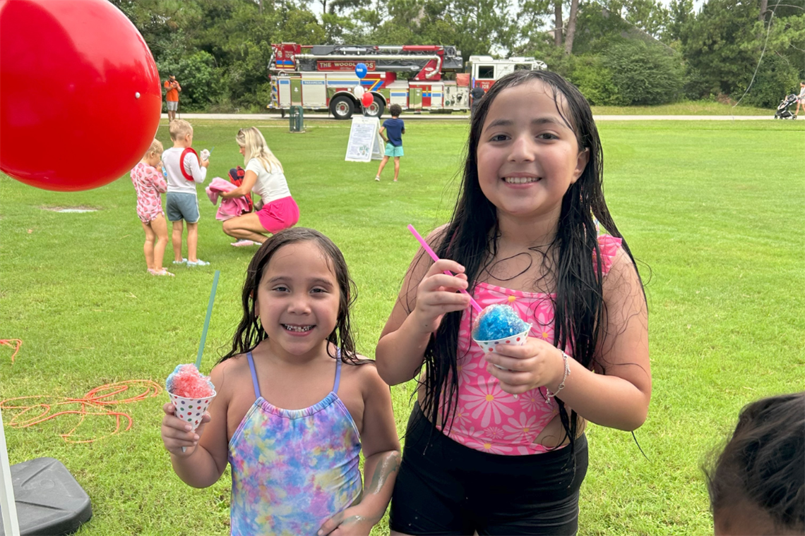 Young children wearing bathing suits holding a snow cone