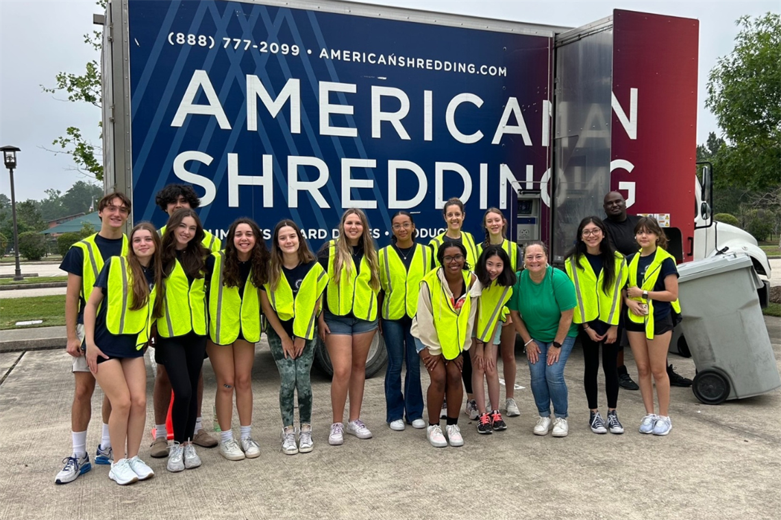 Photo of smiling people in front of a paper recycling truck
