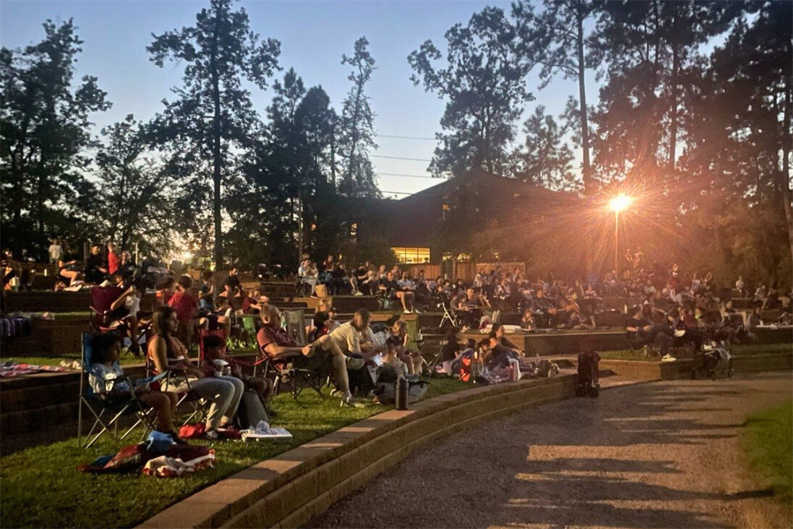 Photo of people sitting in lawn chairs on grass at dusk