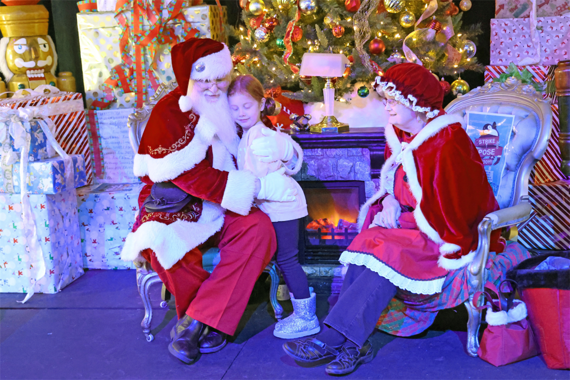 Photo of a child sitting with Santa and Mrs. Claus