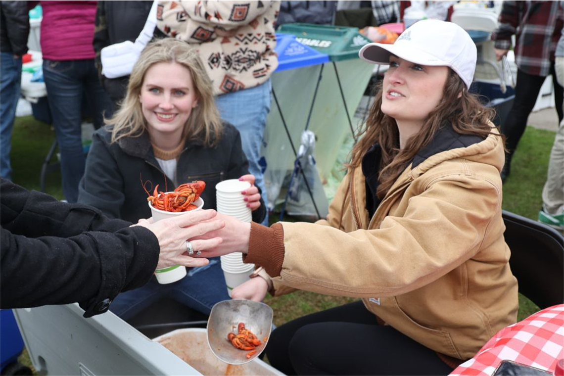 Phot of a smiling lady handing out a cup of crawfish
