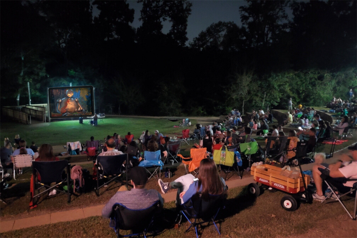 Photo of families sittiing on the lawn watching a big screen