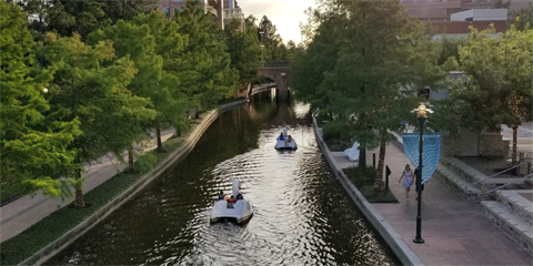 Photo of a canal with swan padel boats gliding through the water