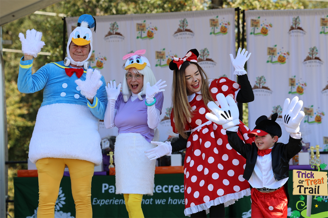 Photo of people dressed in costumes of Mickey Mouse, Donald Duck, Daisy and Minnie Mouse 