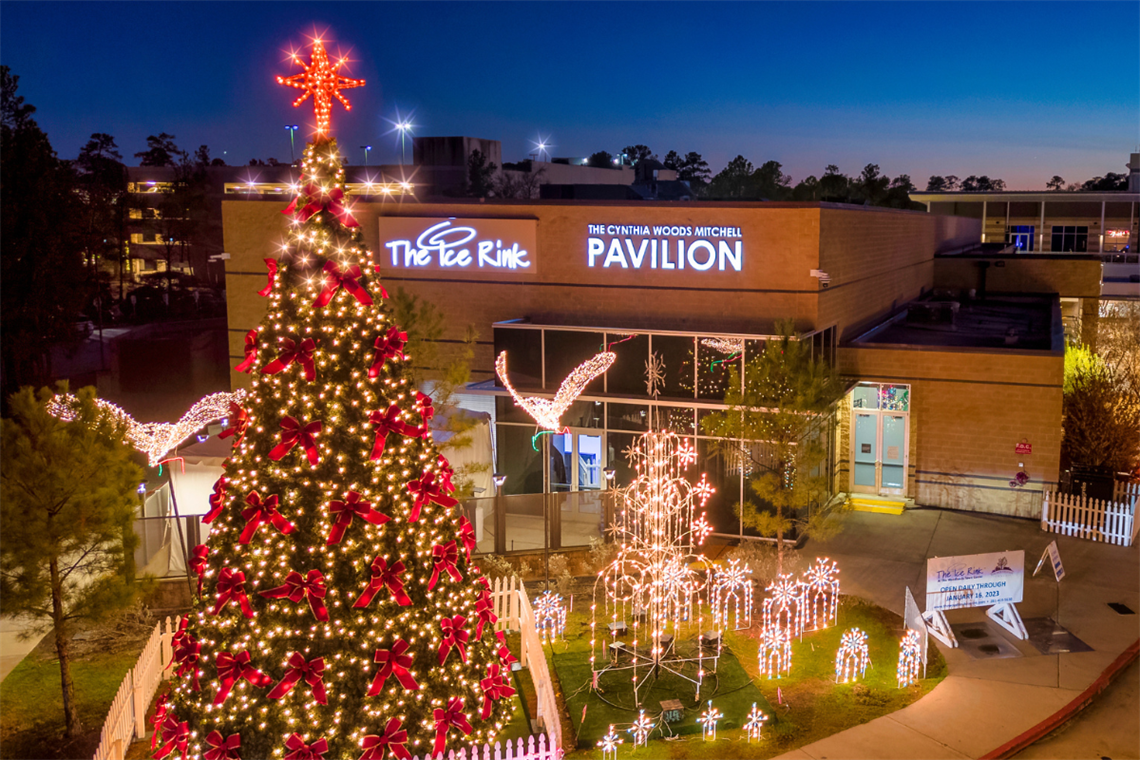 Photo of the outside of the Cynthia Woods Mitchell Pavilion building featuring a large Christmas tree with red bows
