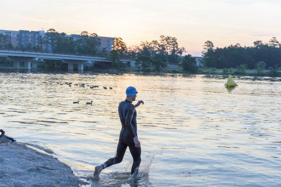 Photo of a triatlon swimmer walking into the water.