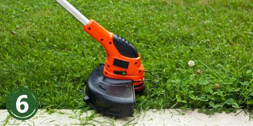 An electric weed edge cutting grass along a sidewalk