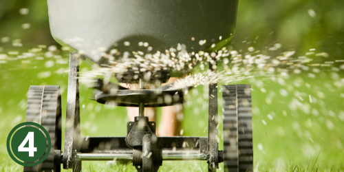 A grey fertilizer bucket spreading granulated seed