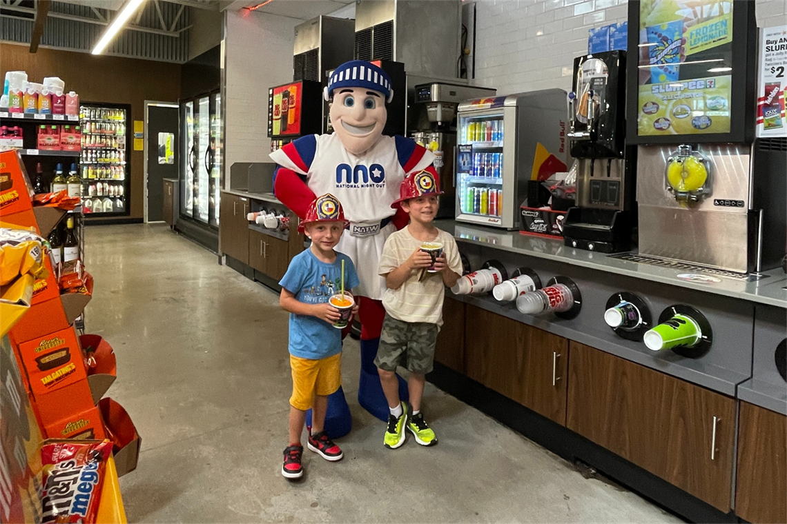 Photo of two smiling children with slurpees and the NNO mascot