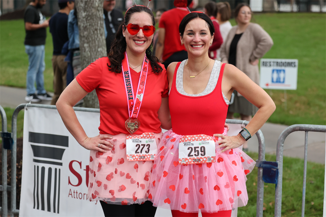 Photo of two smiling runners wearing pink and red skirts